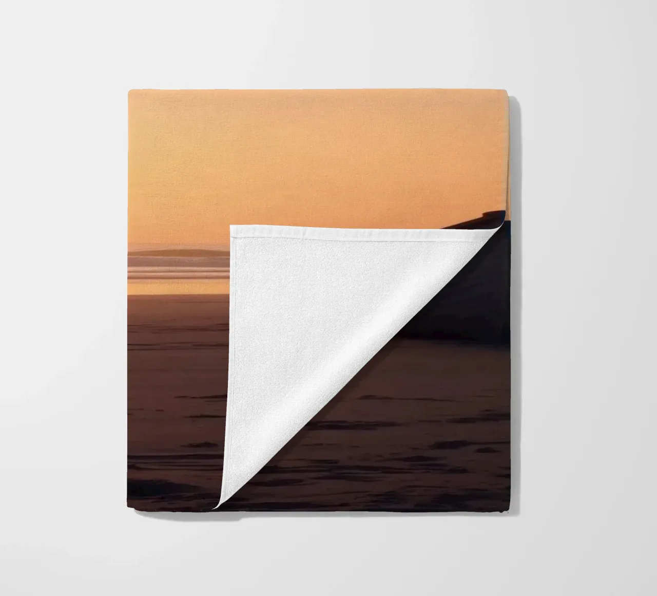 Sunset view with a lone boat on a tranquil beach showcasing beach towel by DesignDoodle