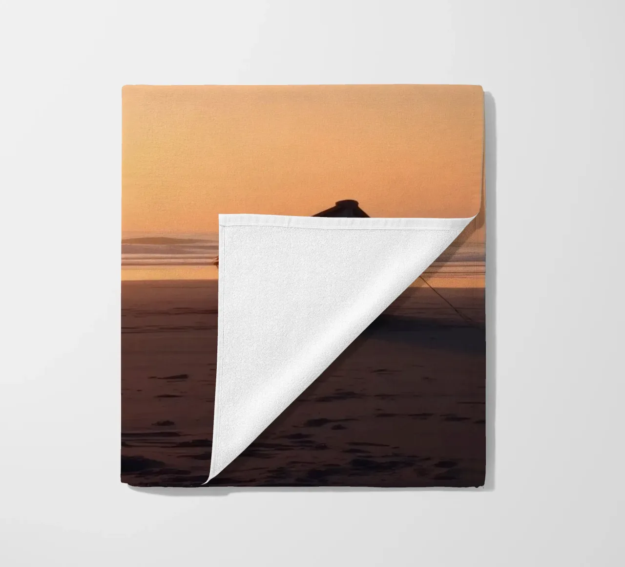 Sunset view with a lone boat on a tranquil beach showcasing beach towel by DesignDoodle
