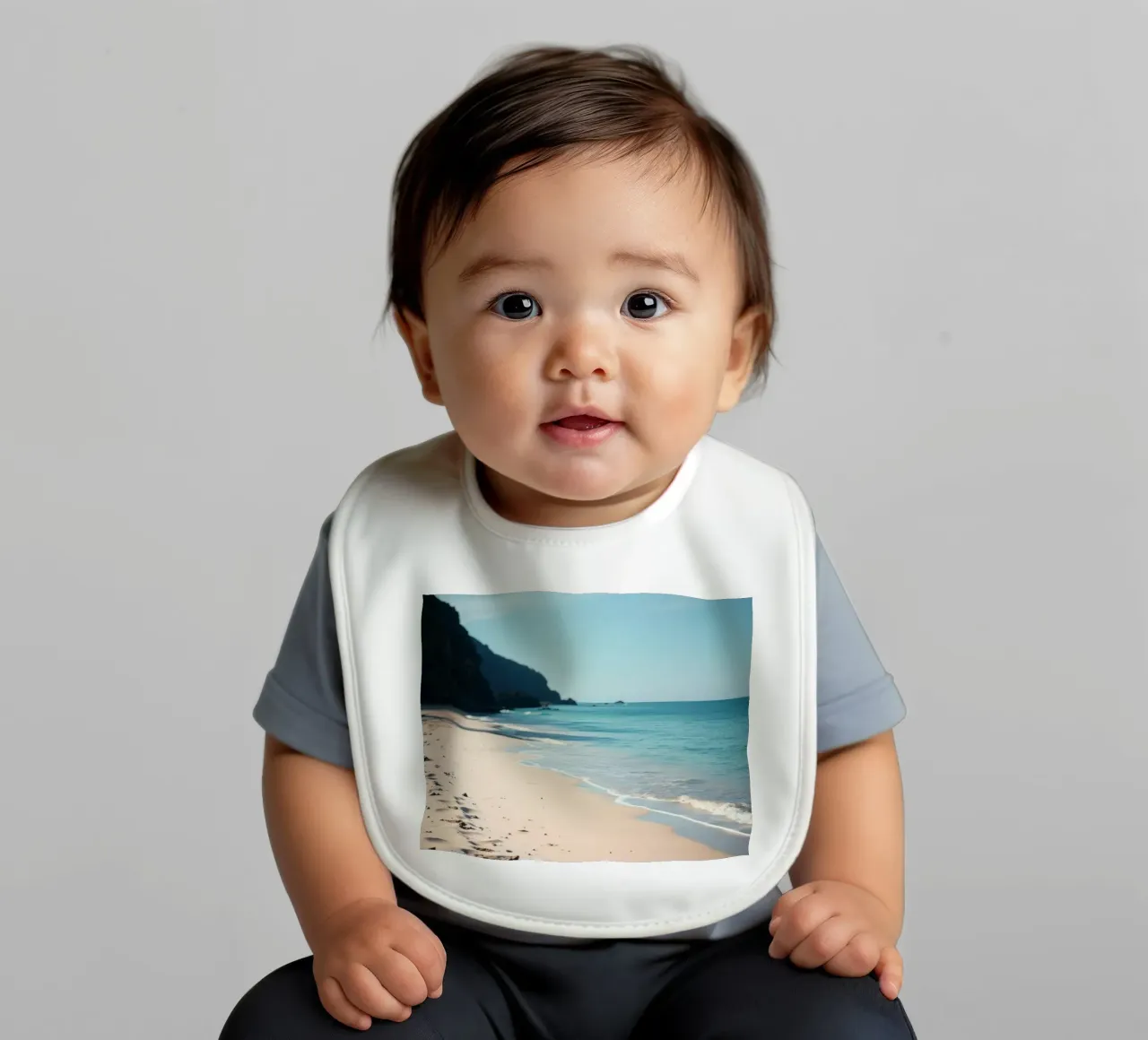 Serene coastline with soft waves lapping against pristine baby bib by DesignDoodle