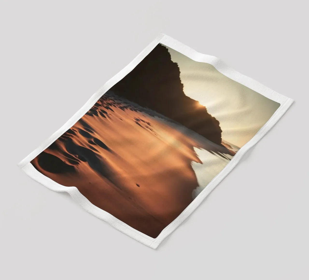 Sunset casts warm glow on sandy beach with gentle waves fleece blanket by DesignDoodle