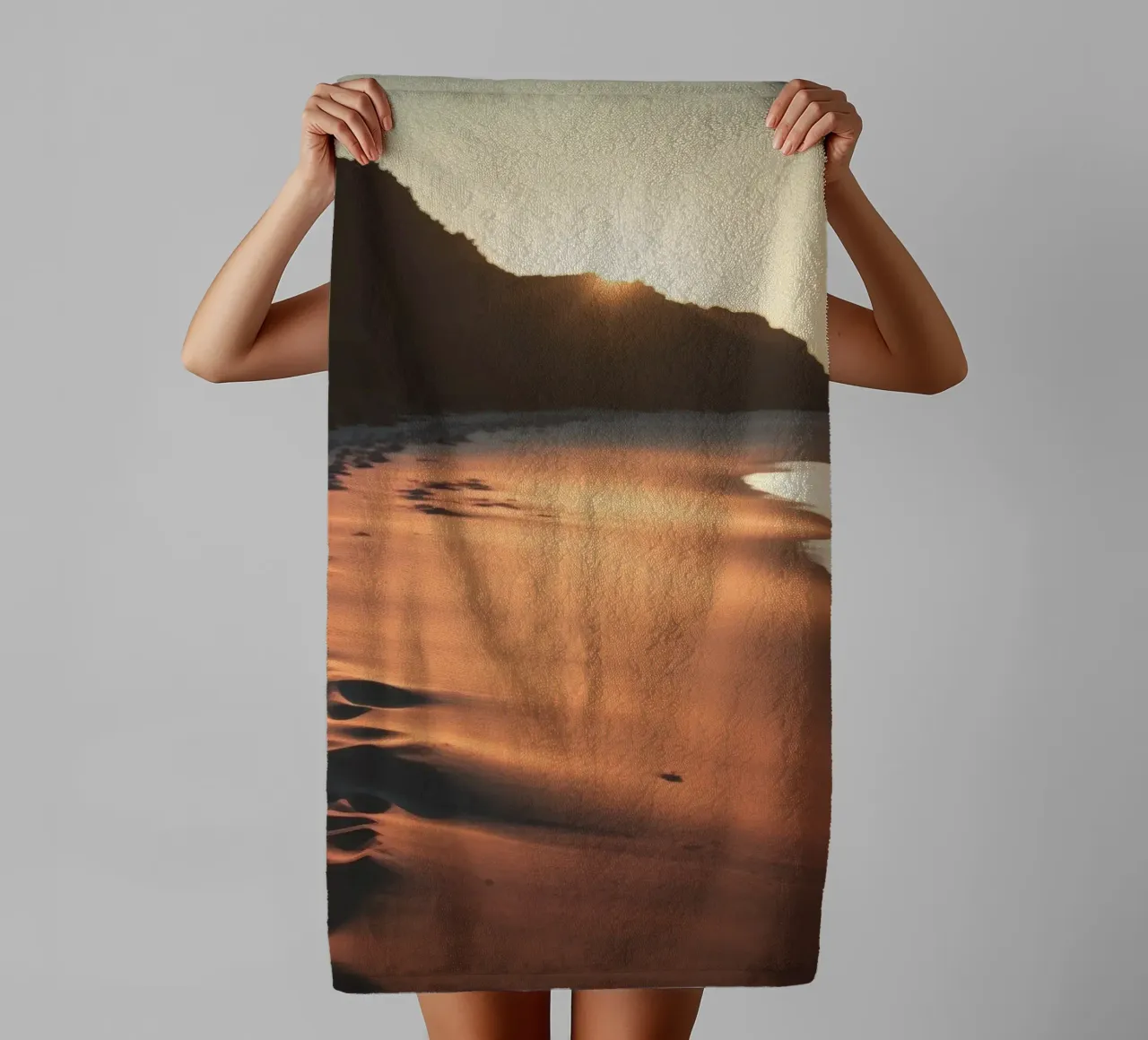 Il tramonto proietta una calda luce sulla spiaggia sabbiosa con le sue dolci onde asciugamano da bagno da DesignDoodle