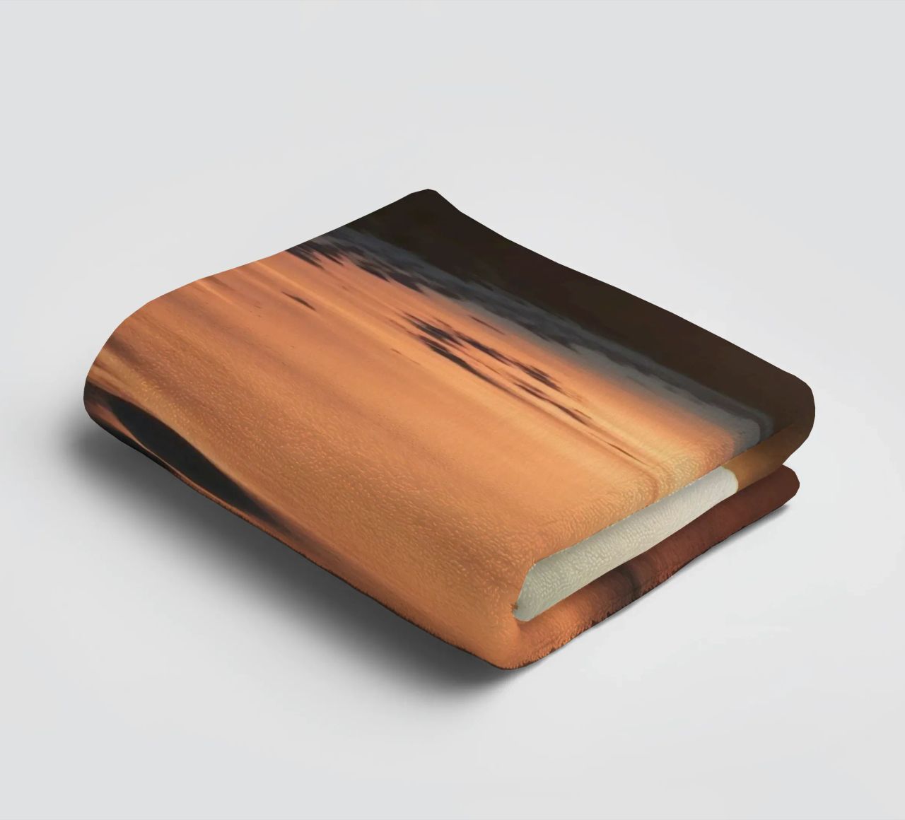 Zonsondergang werpt warme gloed op zandstrand met zachte golven badhanddoek van DesignDoodle