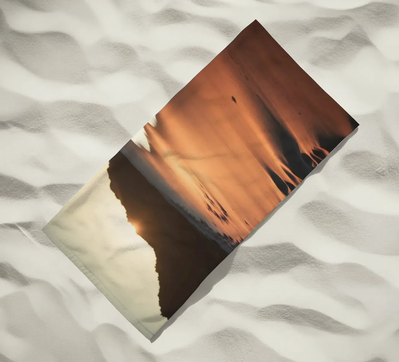 Sunset casts warm glow on sandy beach with gentle waves beach towel by DesignDoodle