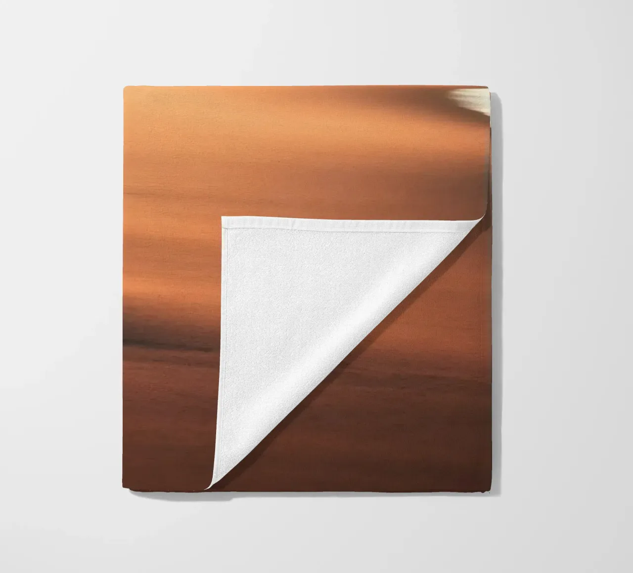 Sunset casts warm glow on sandy beach with gentle waves beach towel by DesignDoodle