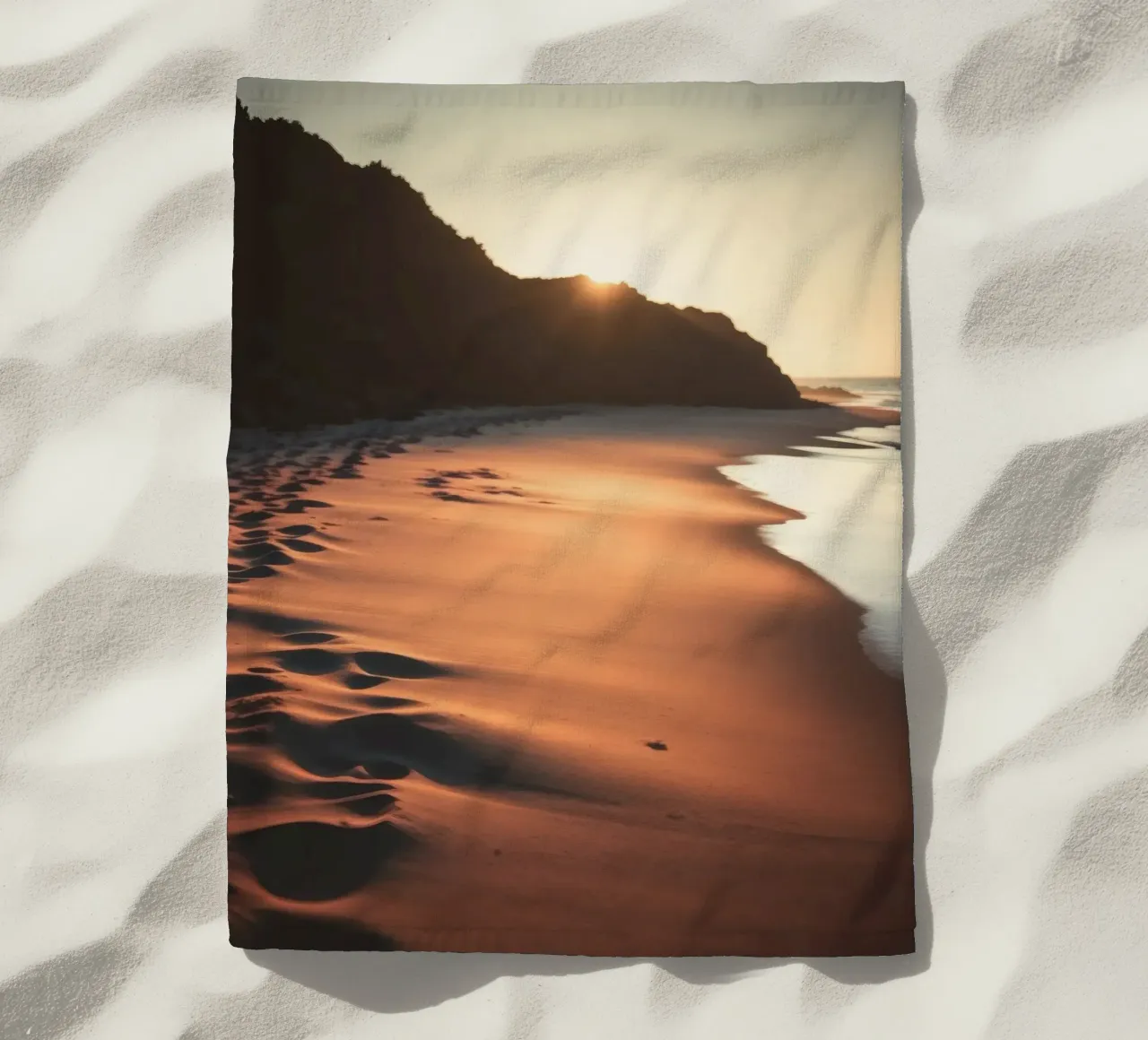 Sunset casts warm glow on sandy beach with gentle waves beach towel by DesignDoodle