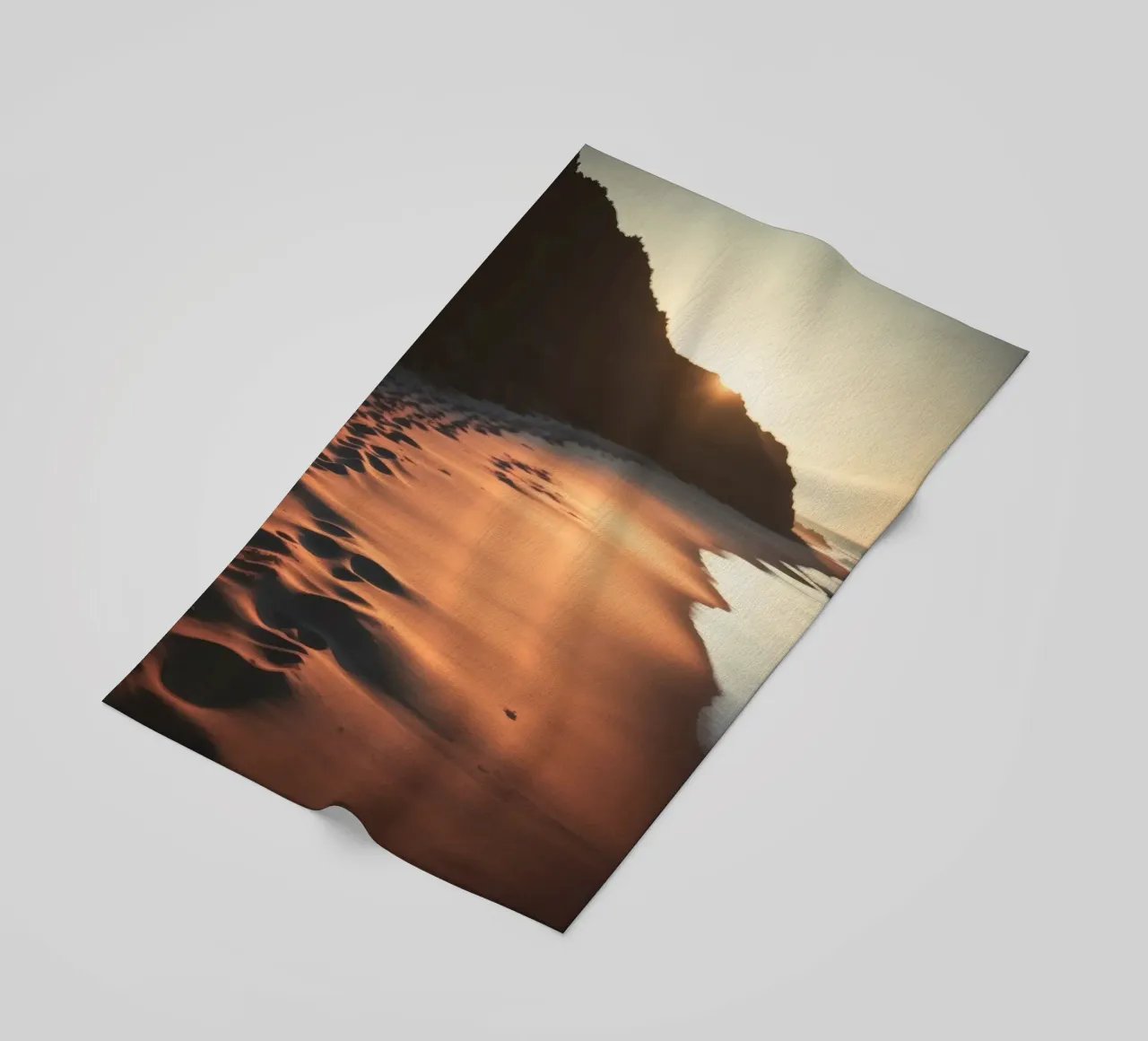 Sunset casts warm glow on sandy beach with gentle waves beach towel by DesignDoodle
