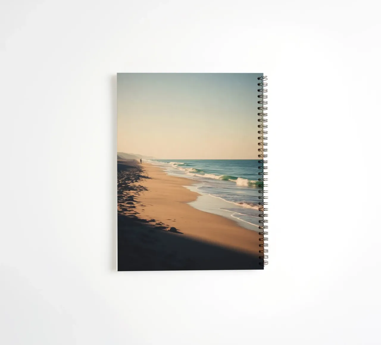 Serene beach view at sunset with gentle waves lapping spiral notebook by DesignDoodle