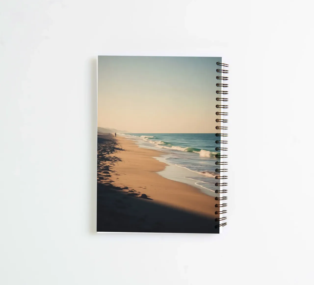 Serene beach view at sunset with gentle waves lapping spiral notebook by DesignDoodle