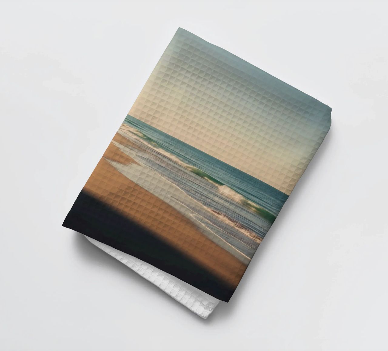 Vue sereine sur la plage au coucher du soleil avec le clapotis des vagues torchon de DesignDoodle