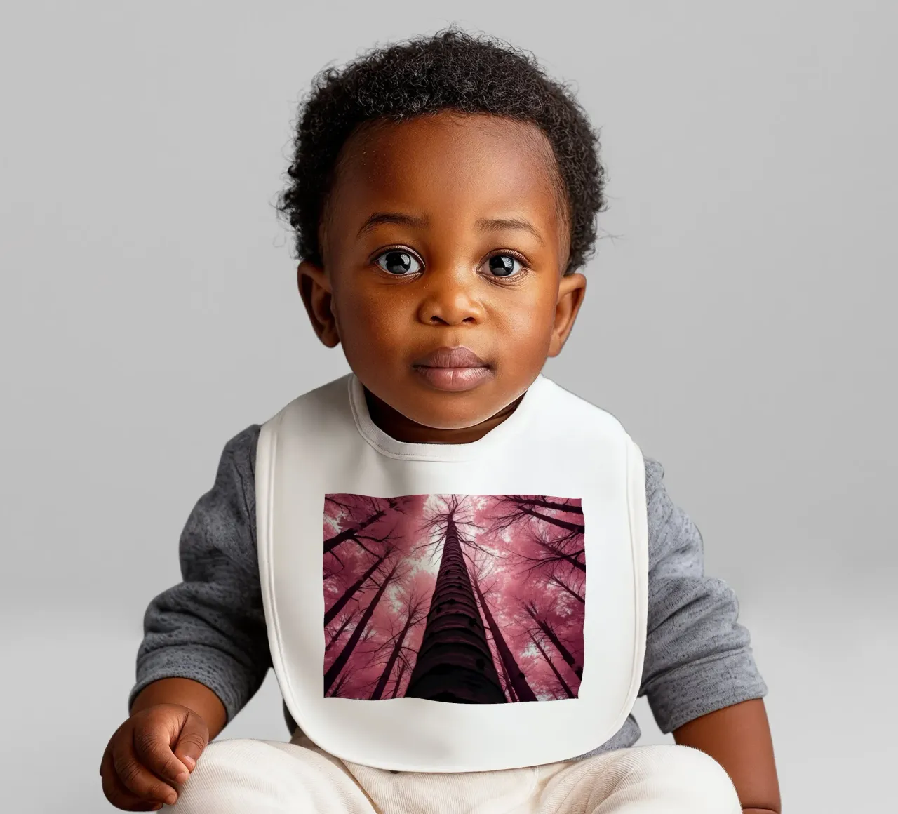 Tall trees stretch towards a pink sky creating a dreamy baby bib by DesignDoodle