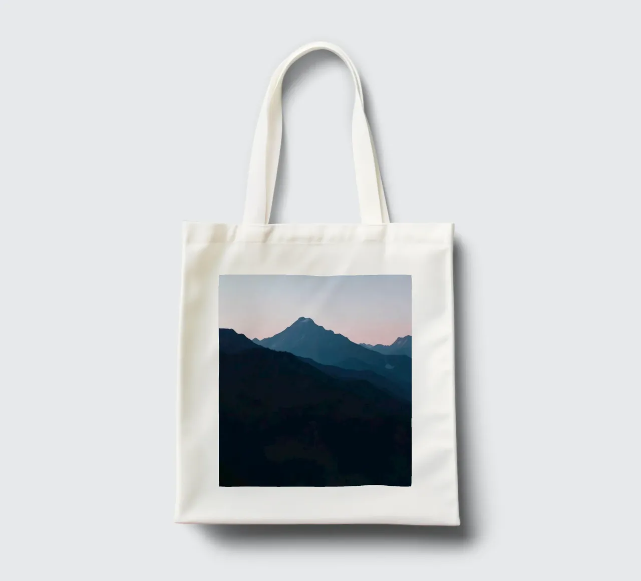 Serene mountain silhouettes at dusk create a tranquil feel tote bag by DesignDoodle