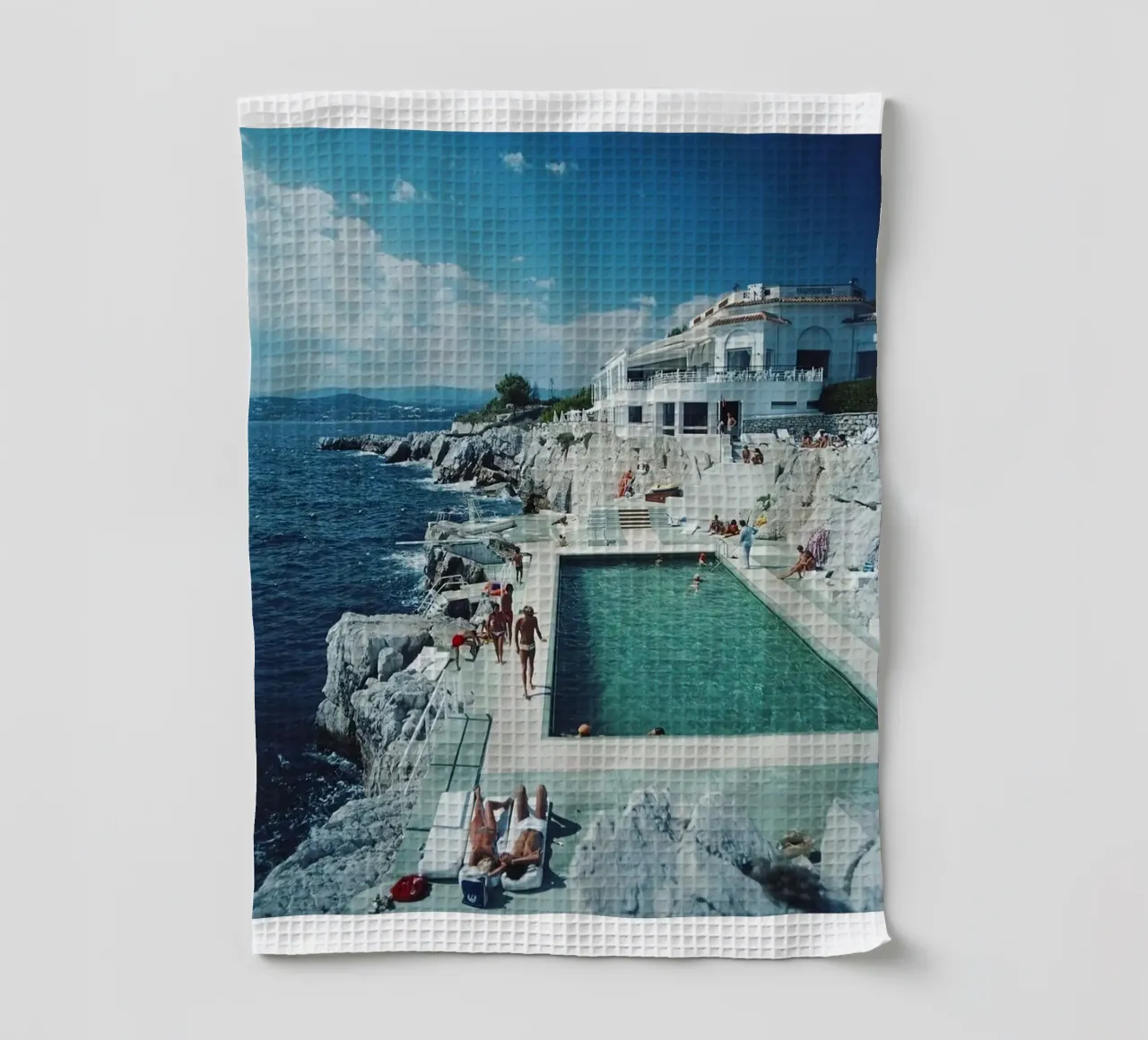 Sunbathing at the Beachside Pool Antibes, 1976 - Slim Aarons tea towel by The Poster UK
