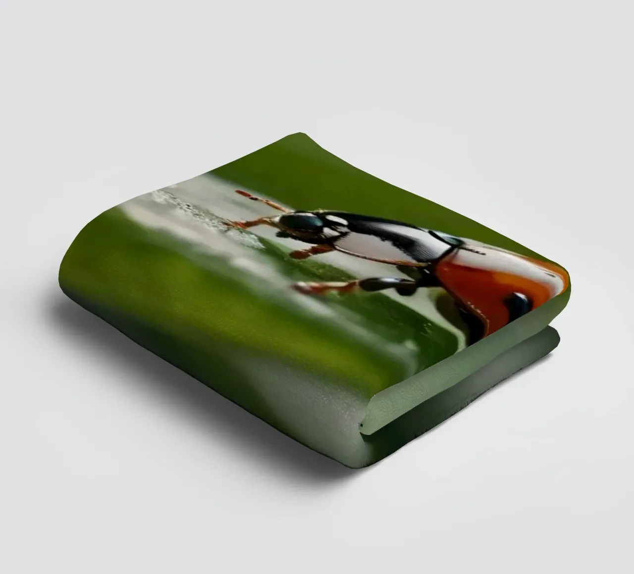 Ladybug crawling on a green leaf adorned with water droplets towel by DesignDoodle
