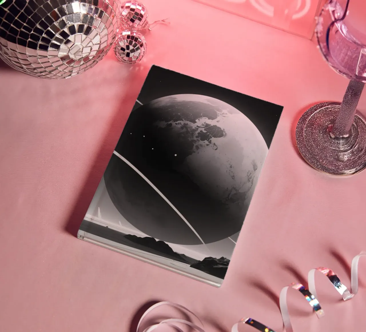 planet with rings hovering over a desolate landscape under a notebook by DesignDoodle