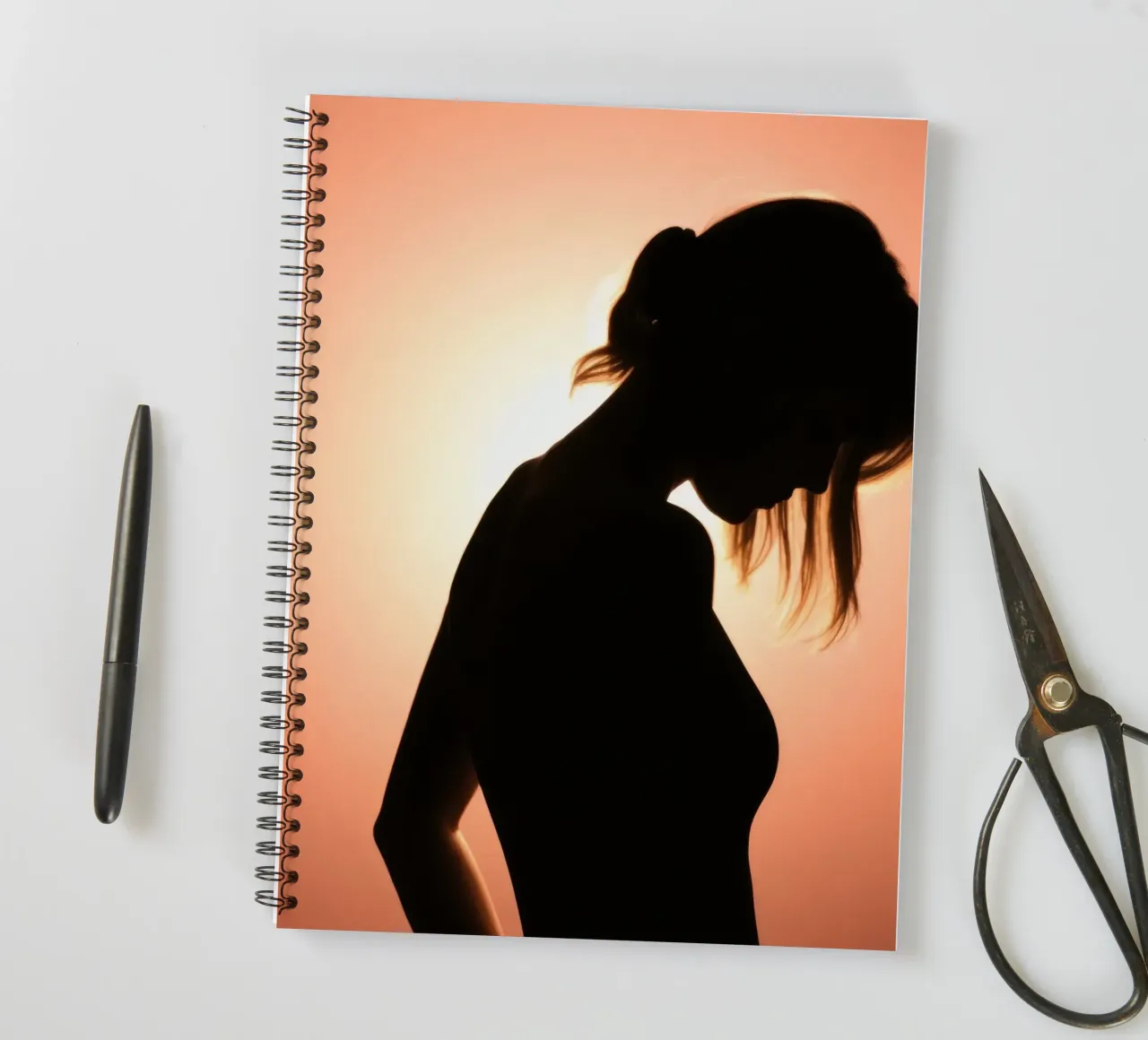 Silhouette einer Frau vor einem atemberaubenden Sonnenuntergang Ringbuch von DesignDoodle