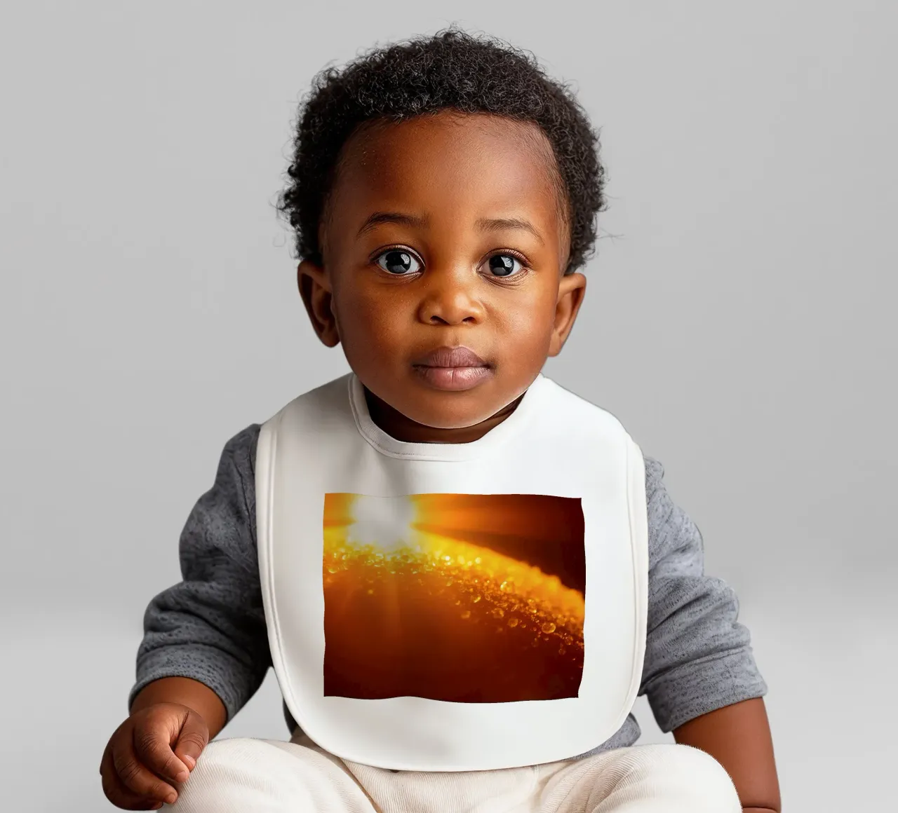 Sunlight glistens on a dewy surface at dawn, creating a warm baby bib by DesignDoodle