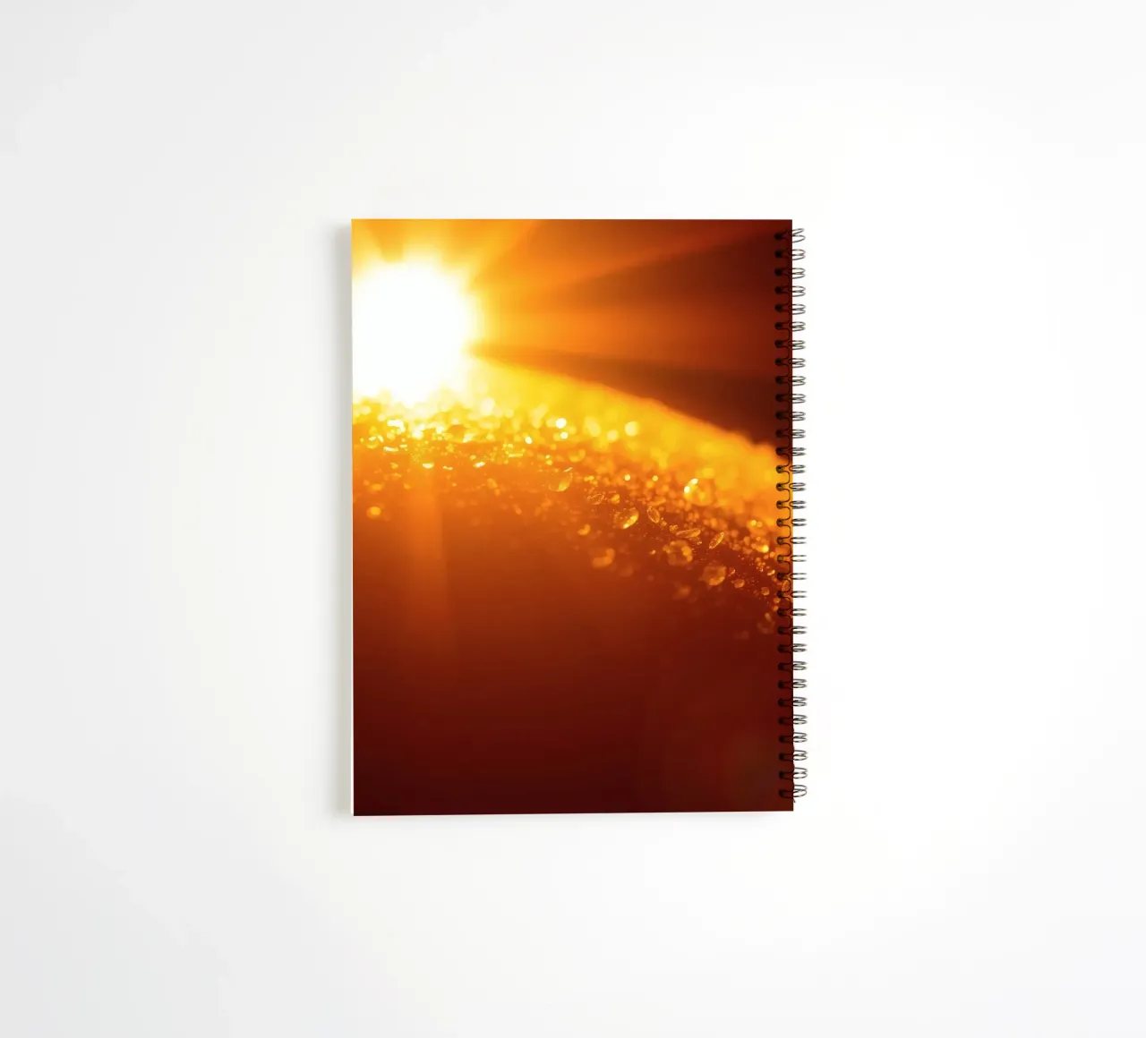 Sunlight glistens on a dewy surface at dawn, creating a warm spiral notebook by DesignDoodle