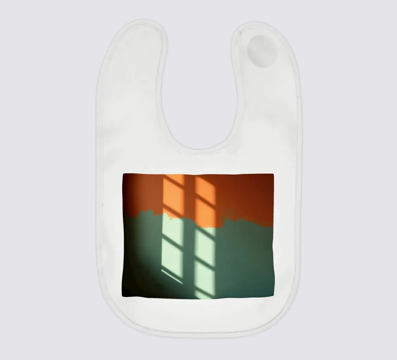 Gioco di luci e ombre su una parete colorata in una stanza illuminata dal sole. bavaglino da DesignDoodle