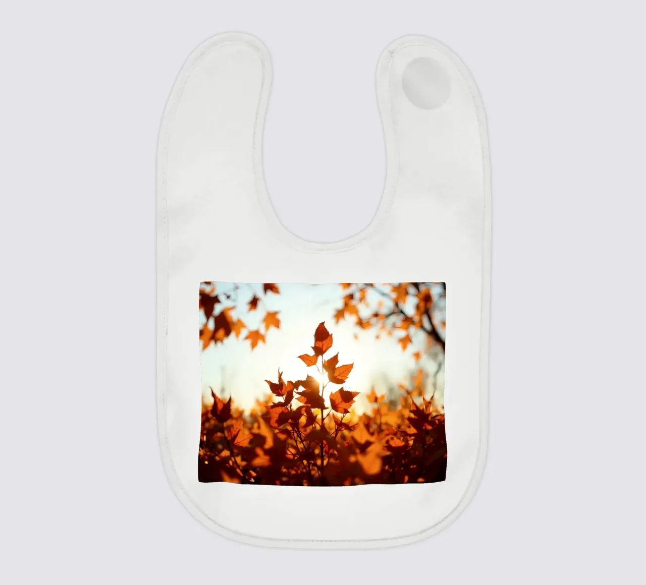 Foglie d'autunno illuminate dalla luce del sole in un ambiente tranquillo. bavaglino da DesignDoodle