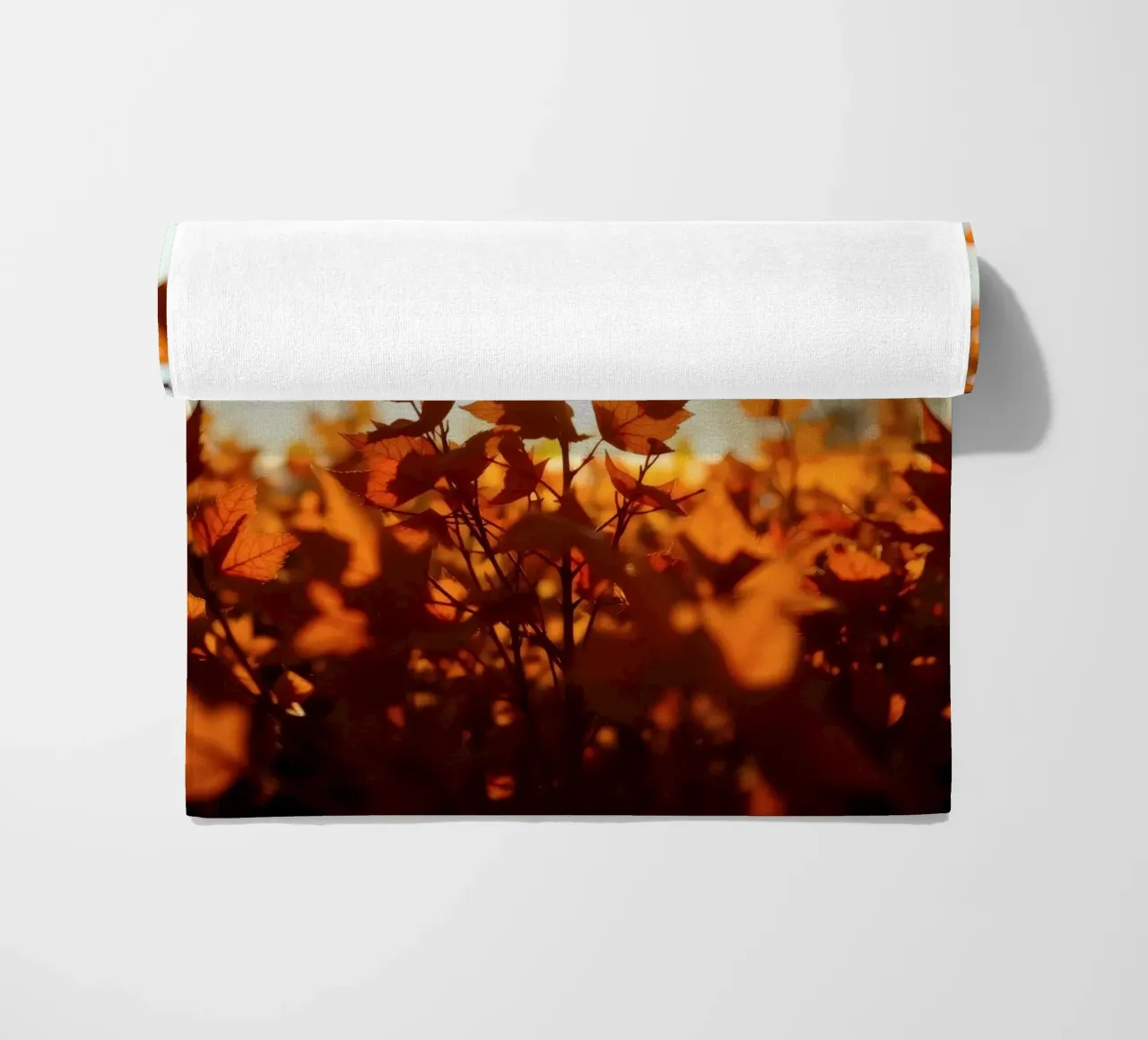 Foglie d'autunno illuminate dalla luce del sole in un ambiente tranquillo. telo mare da DesignDoodle