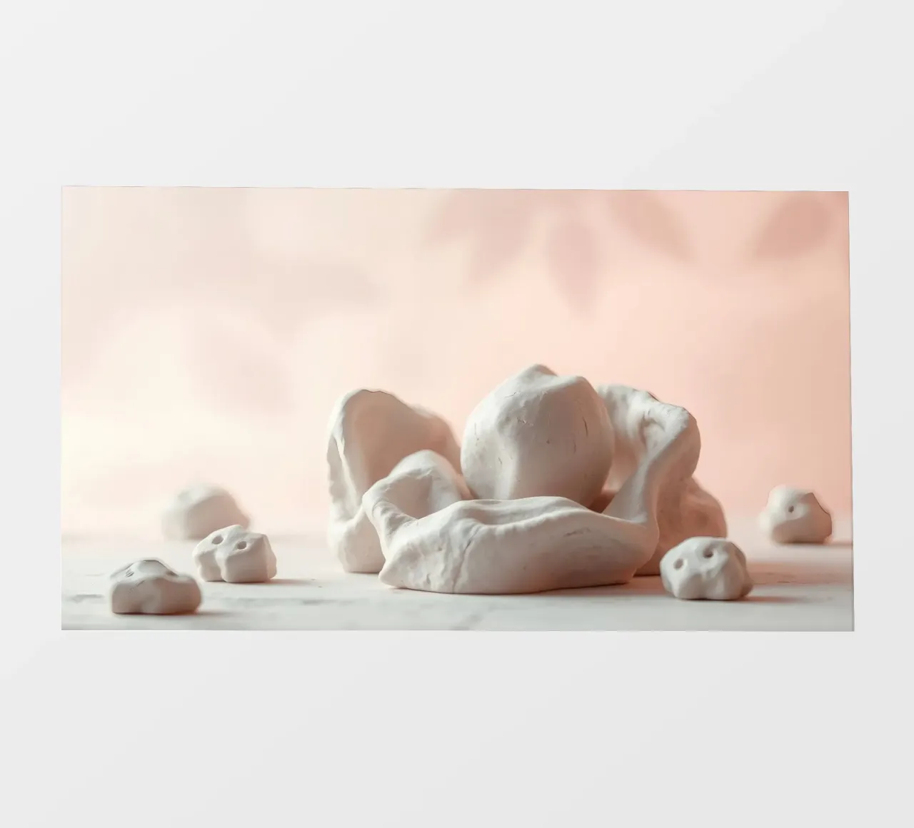 Clay sculptures arranged on a white surface with a soft pink photo wallpaper by DesignDoodle