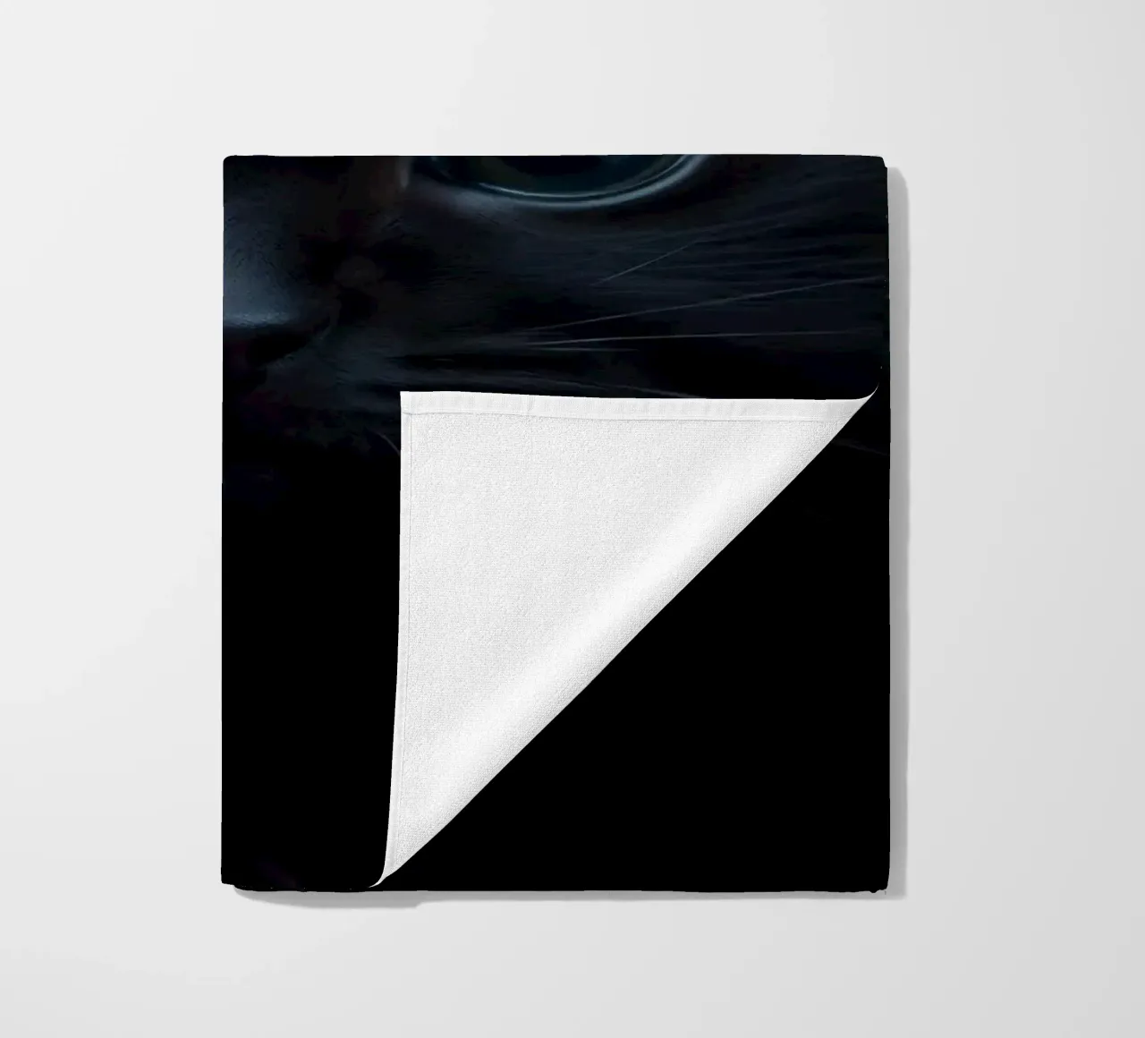 Black kitten with blue eyes gazing curiously against a dark beach towel by DesignDoodle