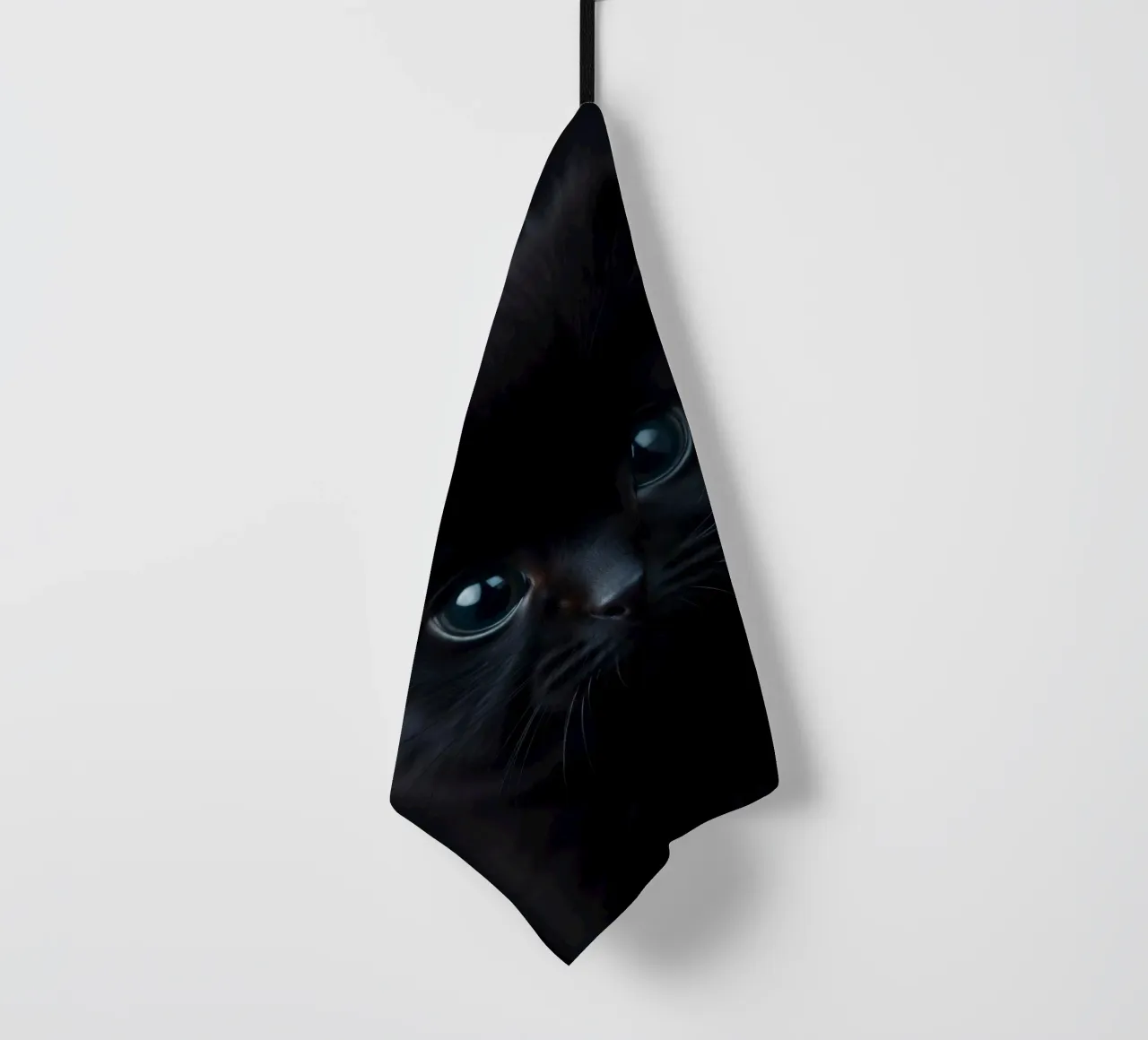 Chaton noir aux yeux bleus regardant curieusement sur un fond sombre. torchon de DesignDoodle