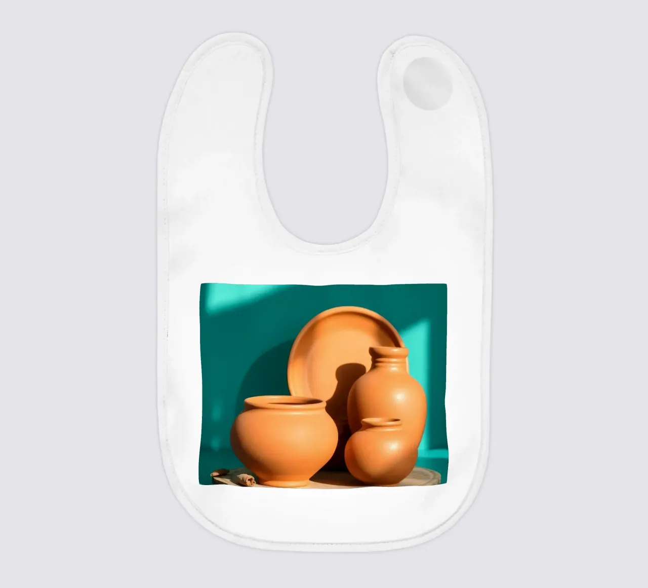Pentole e piatti di terracotta disposti su un piatto di legno bavaglino da DesignDoodle