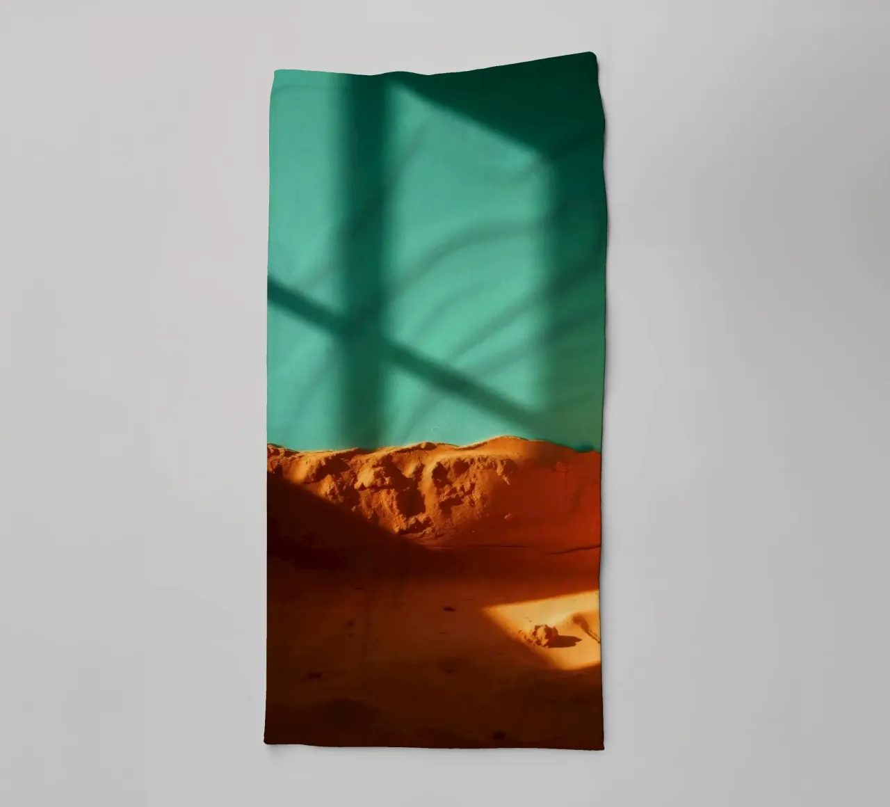 zonlicht werpt geometrische schaduwen op oranje zand en turkoois badhanddoek van DesignDoodle