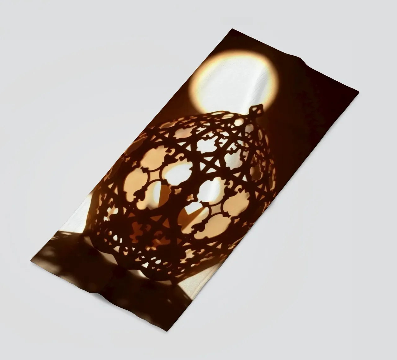 Lanterna dal design complicato che proietta una luce calda al tramonto telo mare da DesignDoodle