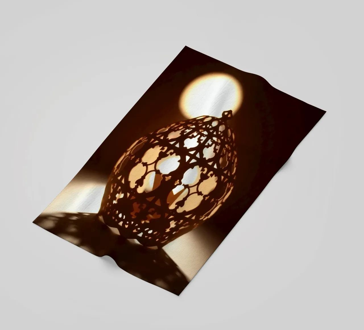 Lanterna dal design complicato che proietta una luce calda al tramonto telo mare da DesignDoodle