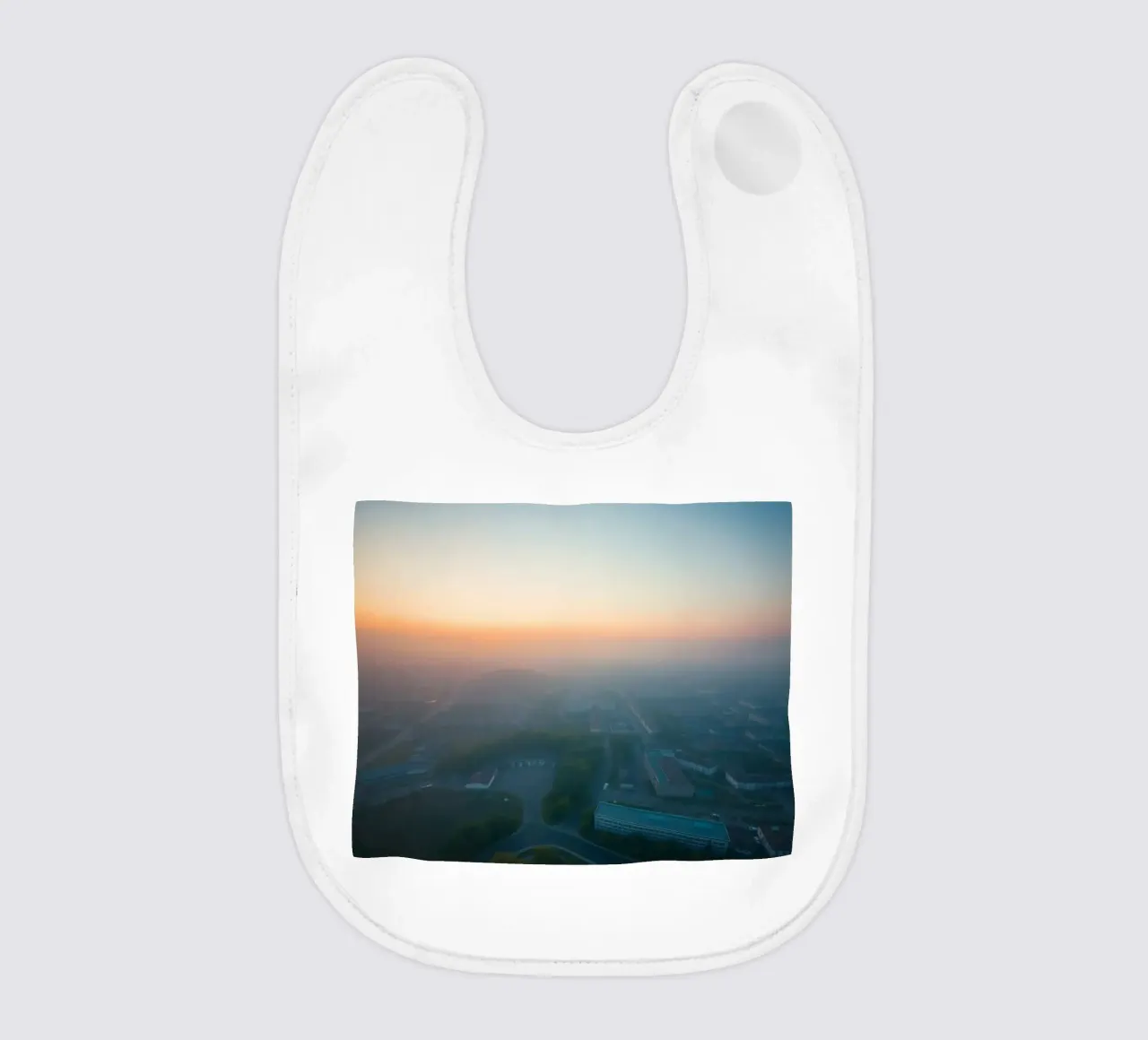 Un'alba nebbiosa su un paesaggio urbano dai tenui colori pastello bavaglino da DesignDoodle