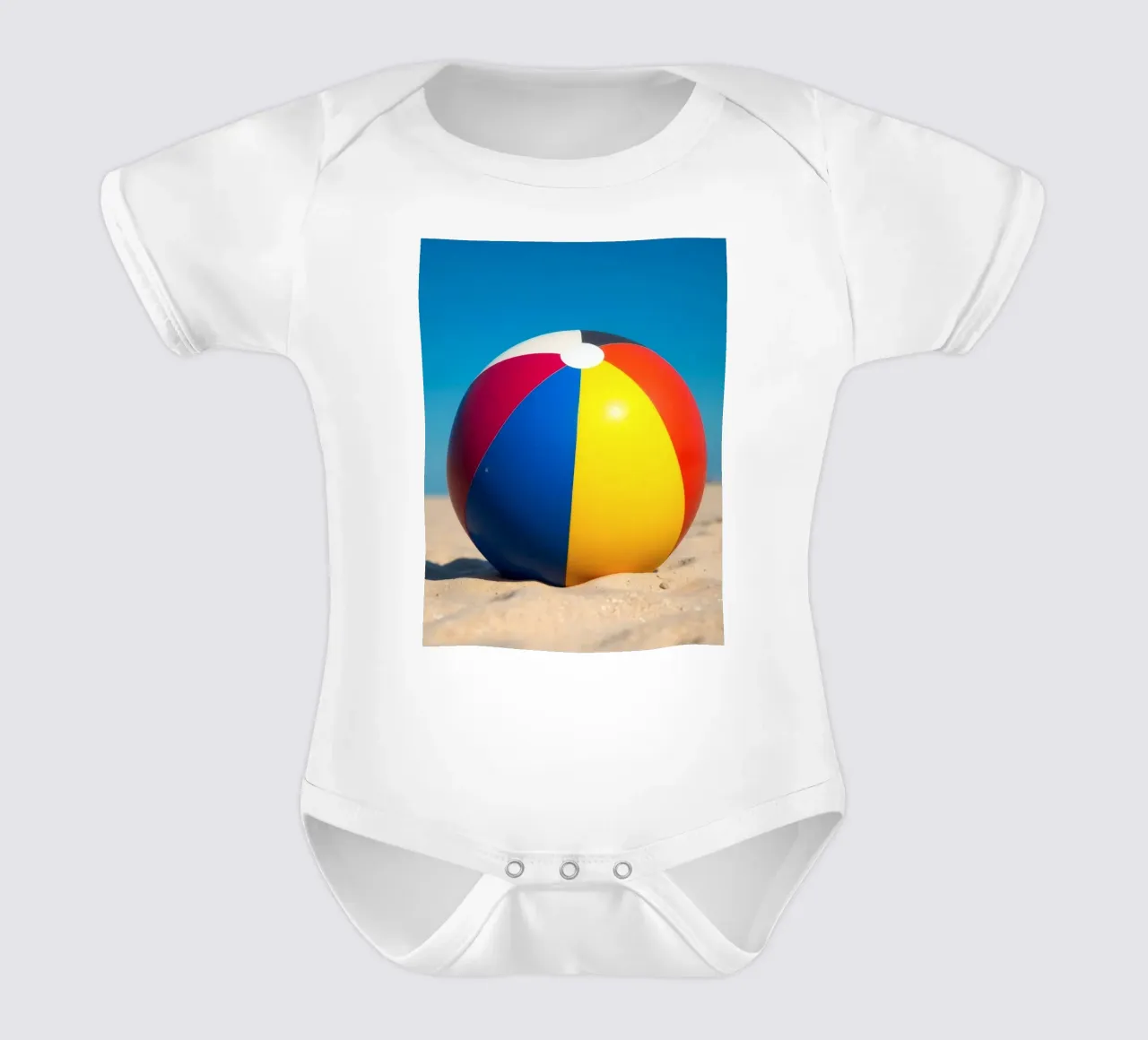 un ballon de plage est posé sur un rivage sablonneux sous un ciel bleu éclatant. body bébé de DesignDoodle