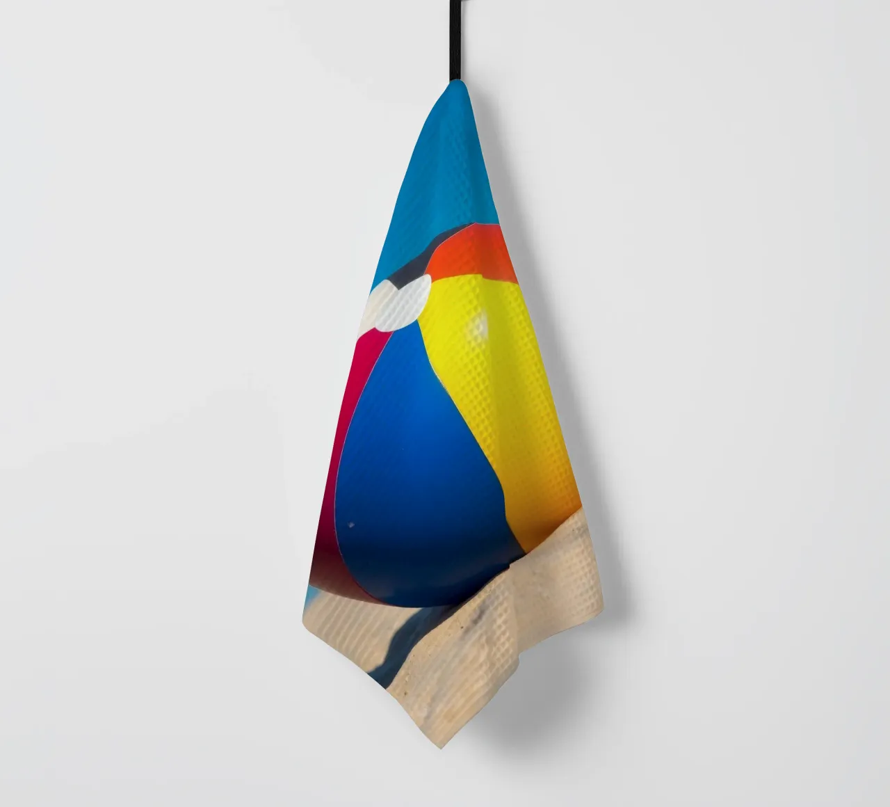 un ballon de plage est posé sur un rivage sablonneux sous un ciel bleu éclatant. torchon de DesignDoodle