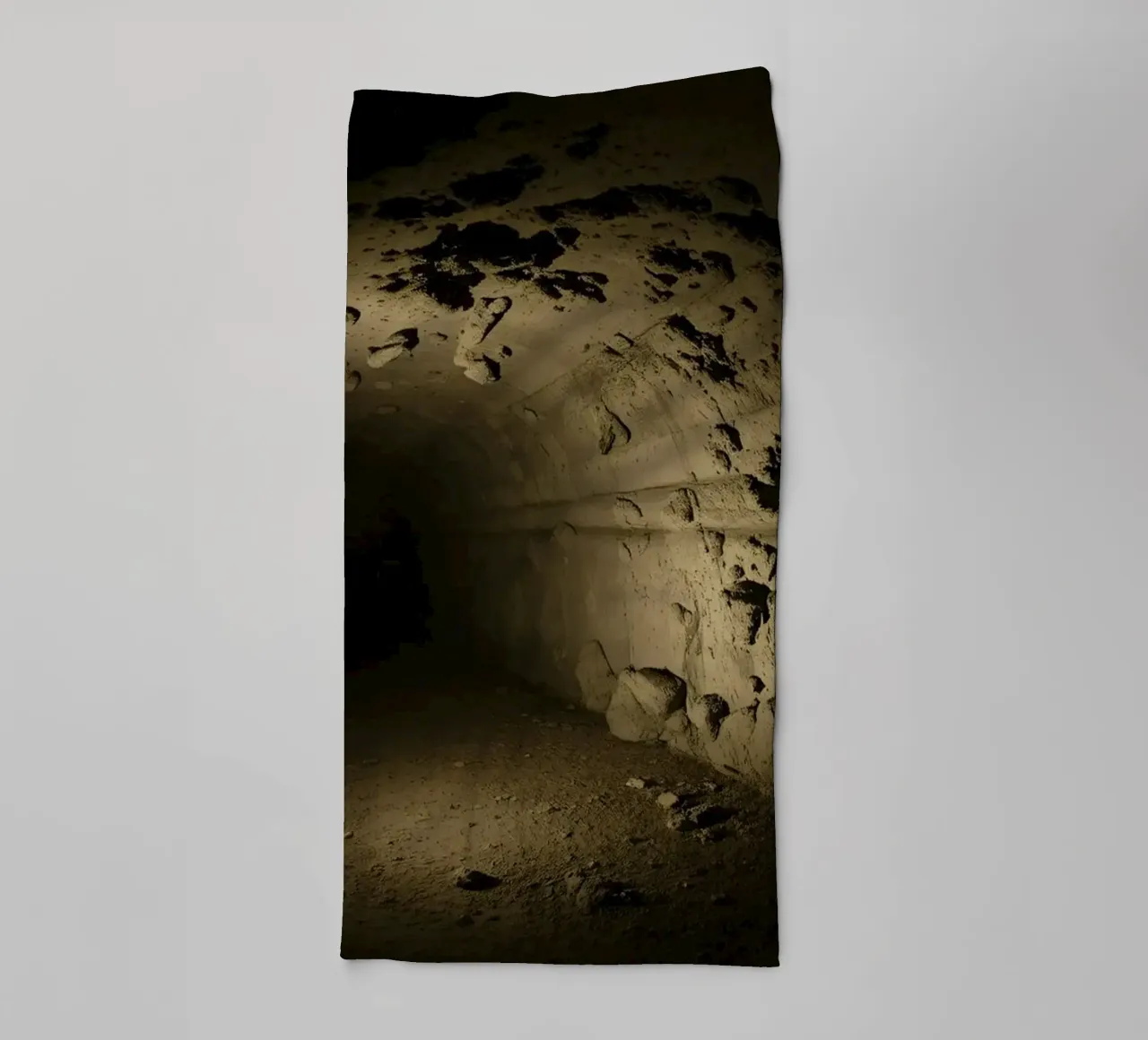A dark, mysterious tunnel with rocky walls illuminated towel by DesignDoodle