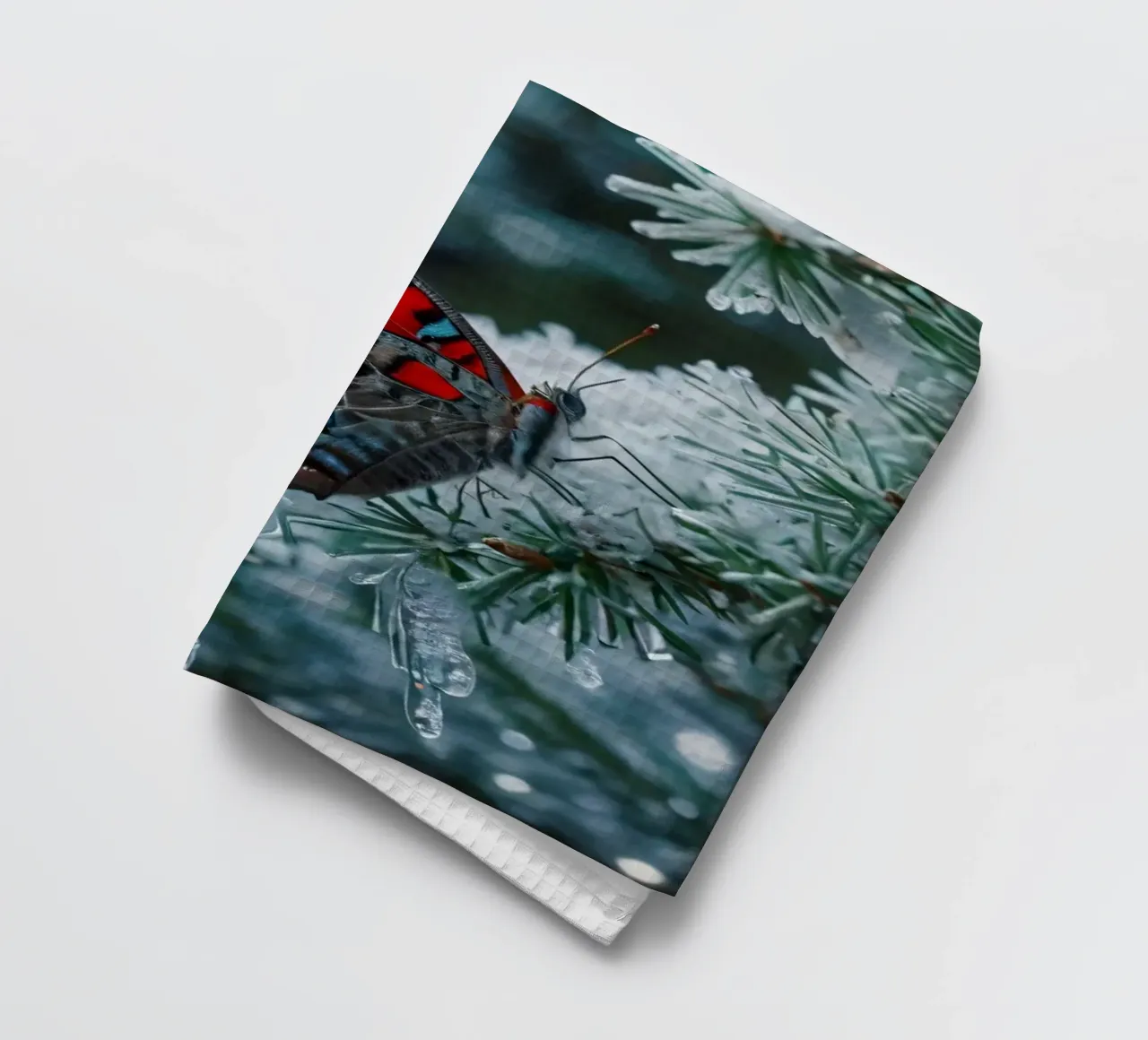 A butterfly resting on evergreen branches covered in frost tea towel by DesignDoodle