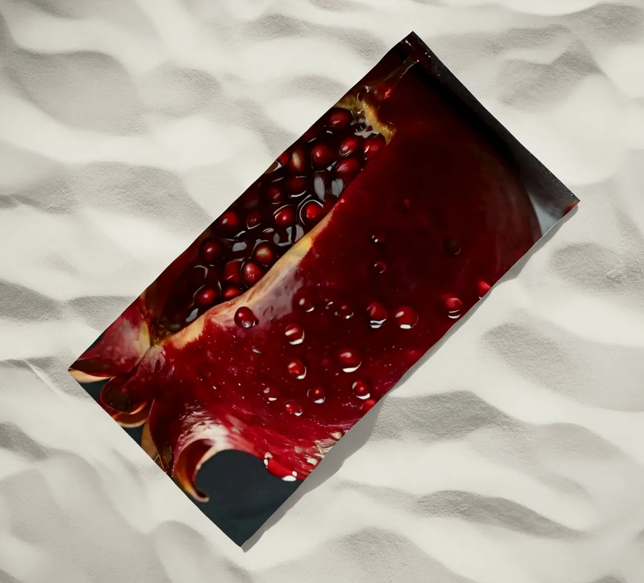 Freshly sliced pomegranate resting on a dark surface surroun beach towel by DesignDoodle