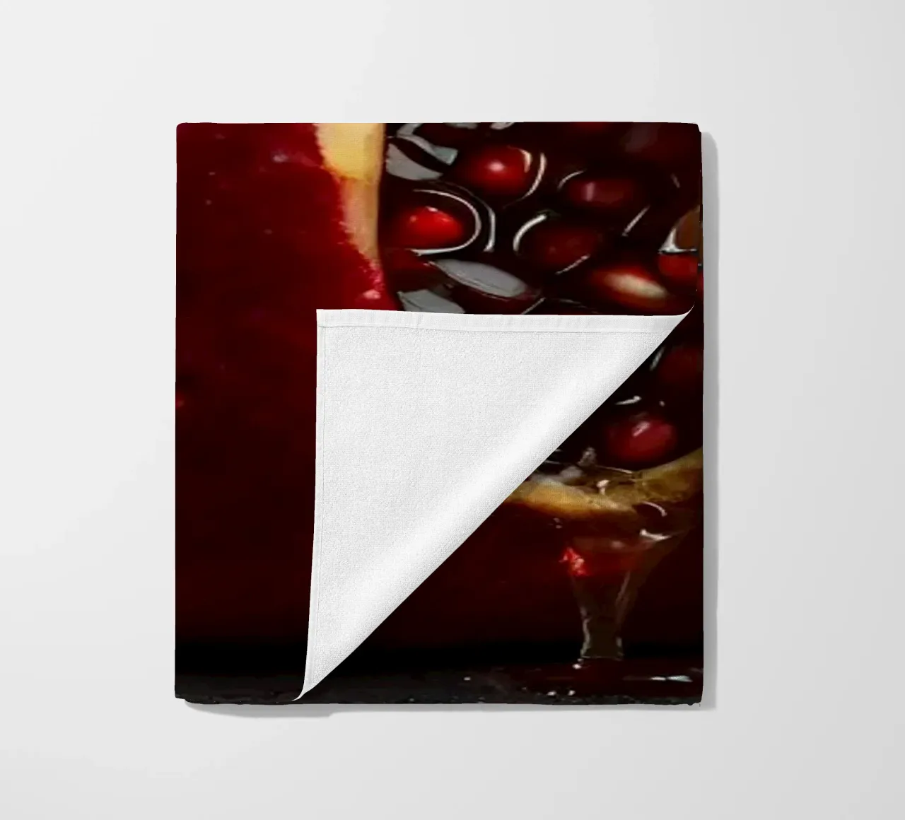 Freshly sliced pomegranate resting on a dark surface surroun beach towel by DesignDoodle