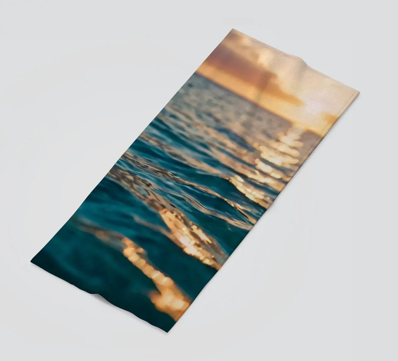 Le calme onde dell'oceano riflettono un tramonto vibrante su un mare calmo. telo mare da DesignDoodle