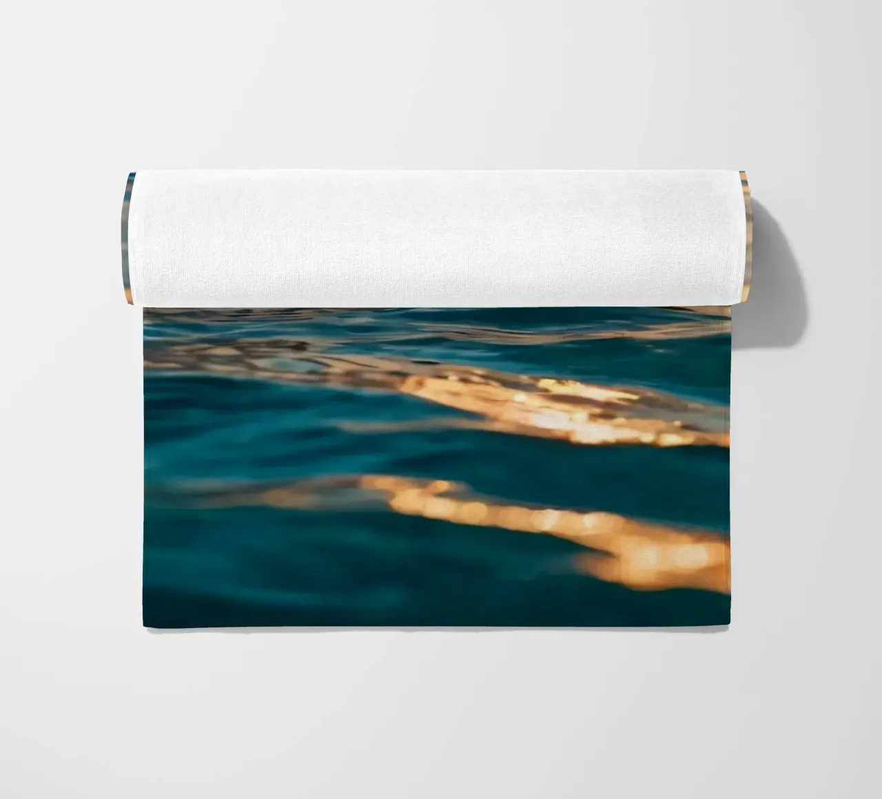 Le calme onde dell'oceano riflettono un tramonto vibrante su un mare calmo. telo mare da DesignDoodle
