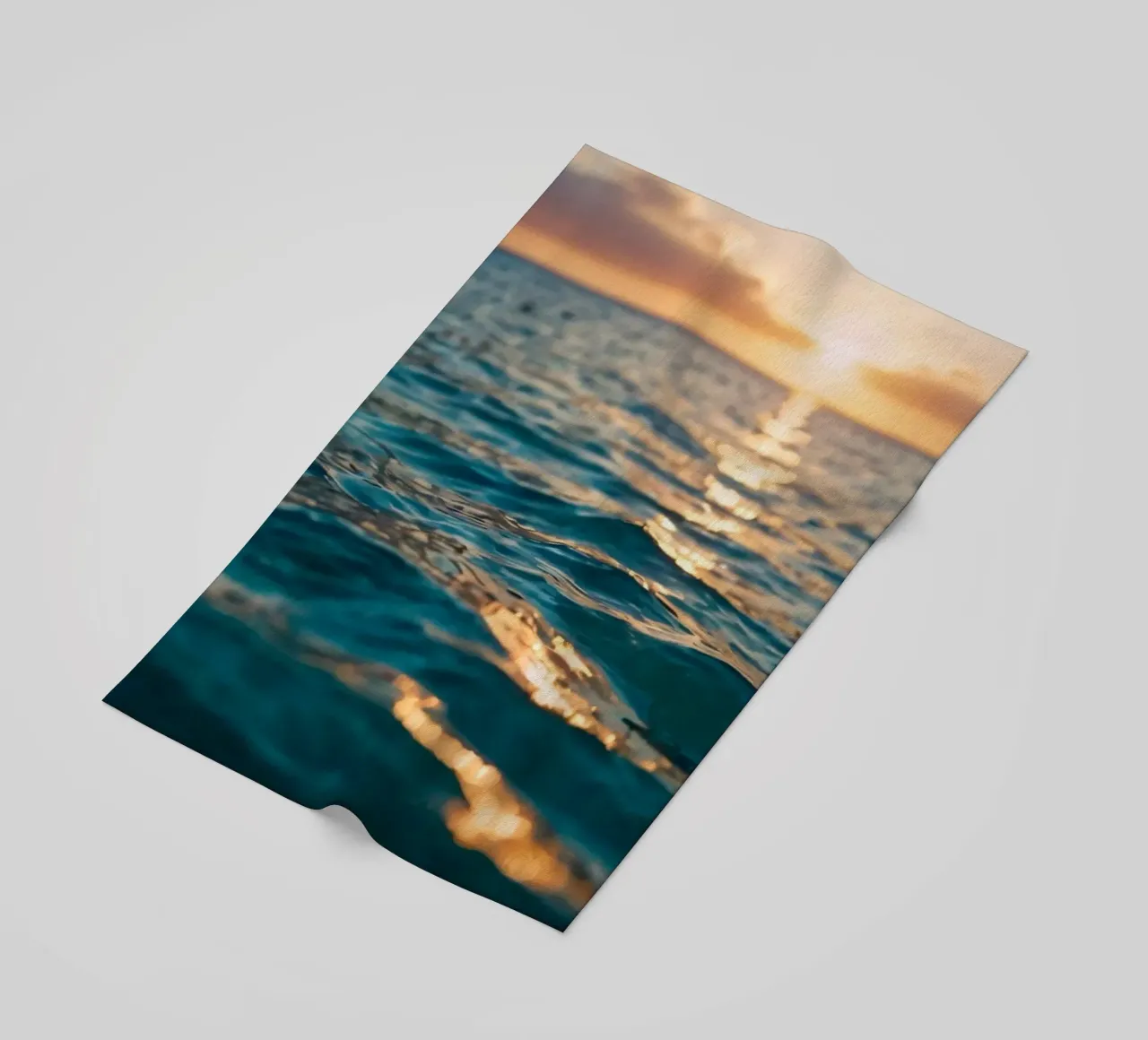 Le calme onde dell'oceano riflettono un tramonto vibrante su un mare calmo. telo mare da DesignDoodle