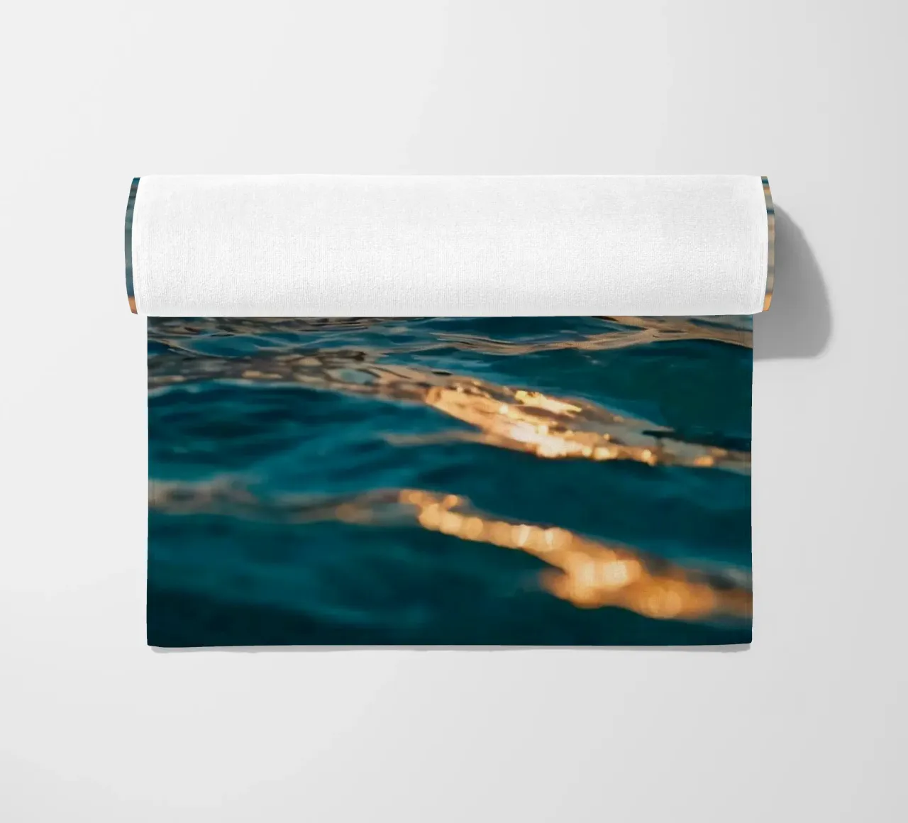 Le calme onde dell'oceano riflettono un tramonto vibrante su un mare calmo. telo mare da DesignDoodle