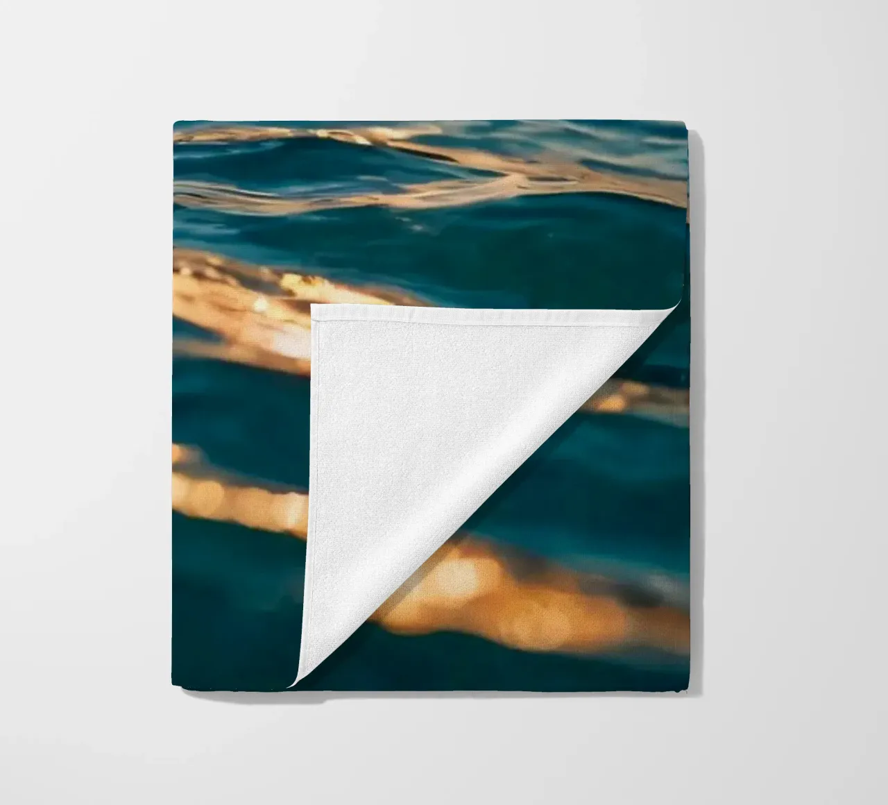 Le calme onde dell'oceano riflettono un tramonto vibrante su un mare calmo. telo mare da DesignDoodle