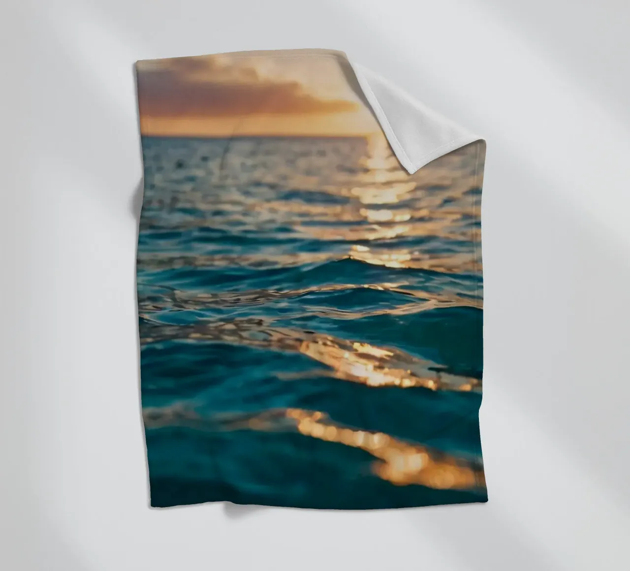 calm ocean waves reflect a vibrant sunset over calm wate fleece blanket by DesignDoodle