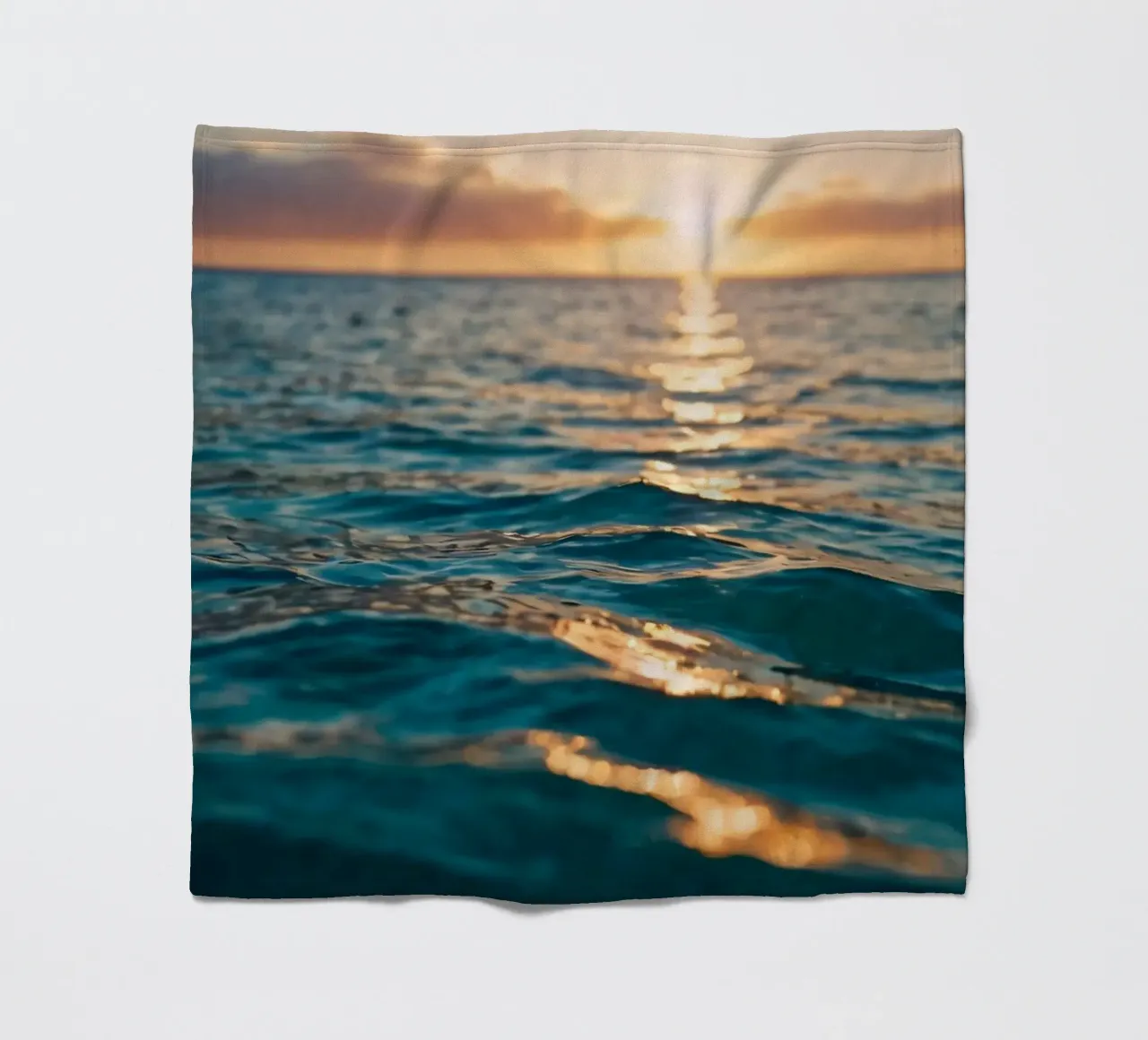 calm ocean waves reflect a vibrant sunset over calm wate fleece blanket by DesignDoodle