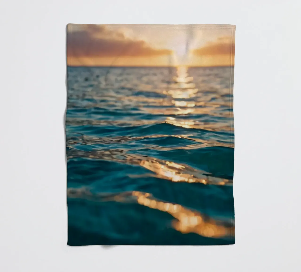 calm ocean waves reflect a vibrant sunset over calm wate fleece blanket by DesignDoodle