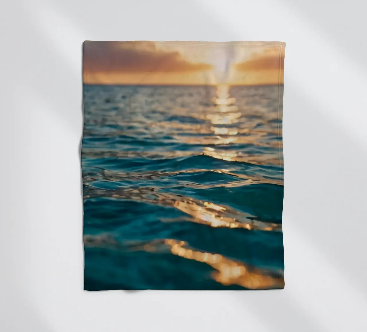 calm ocean waves reflect a vibrant sunset over calm wate fleece blanket by DesignDoodle