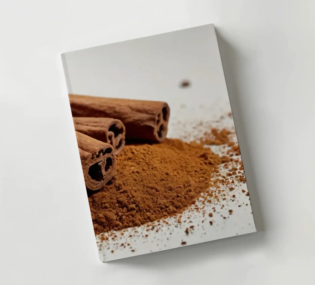 Cinnamon sticks and powder arranged neatly on white surface notebook by DesignDoodle