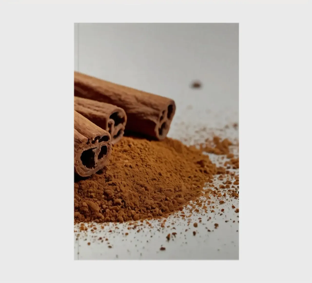 Cinnamon sticks and powder arranged neatly on white surface notebook by DesignDoodle