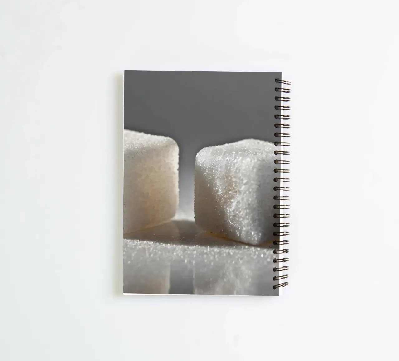 Two sugar cubes on a reflective surface with soft lighting spiral notebook by DesignDoodle